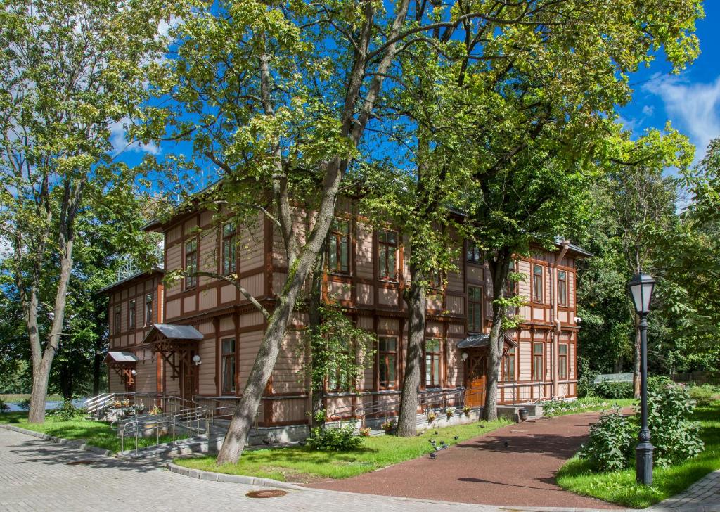 un edificio de madera con árboles delante de él en Guest House na Maloy Nevke, en San Petersburgo