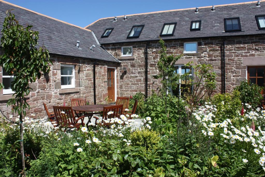 a garden with a table and chairs in front of a building at Anniston Farm Cottages in Inverbervie