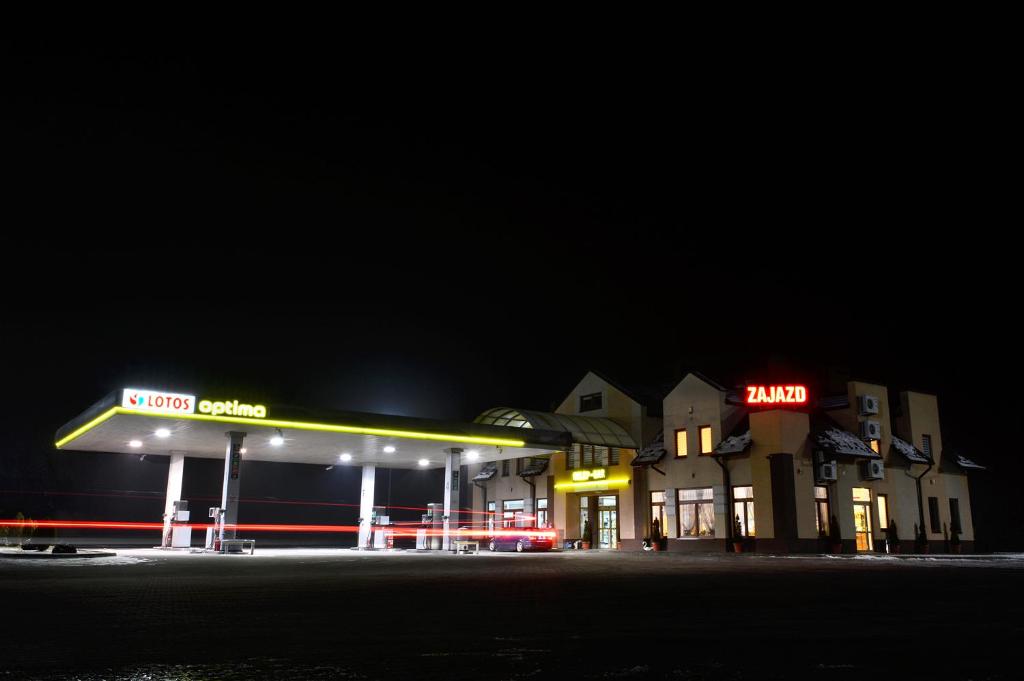 una gasolinera de noche con letreros de neón. en Zajazd Partynia, en Partynia