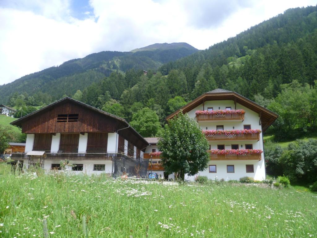 a building in the middle of a field with mountains at Hotel Pension Moarhof in Vallarga