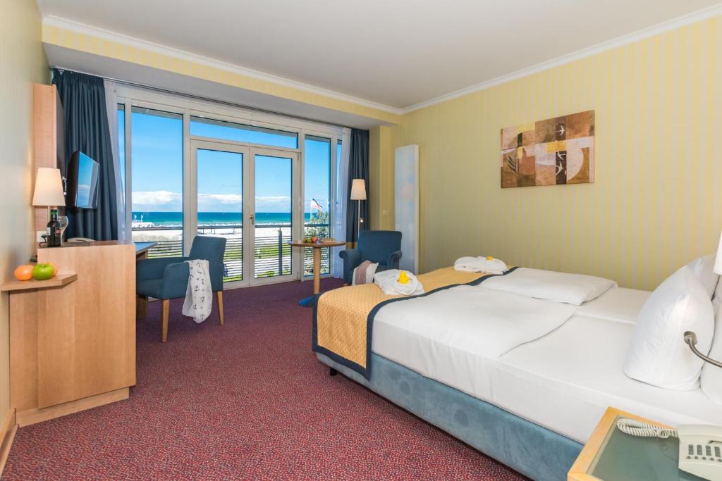 a hotel room with a bed and a view of the ocean at Strand-Hotel Hübner in Warnemünde