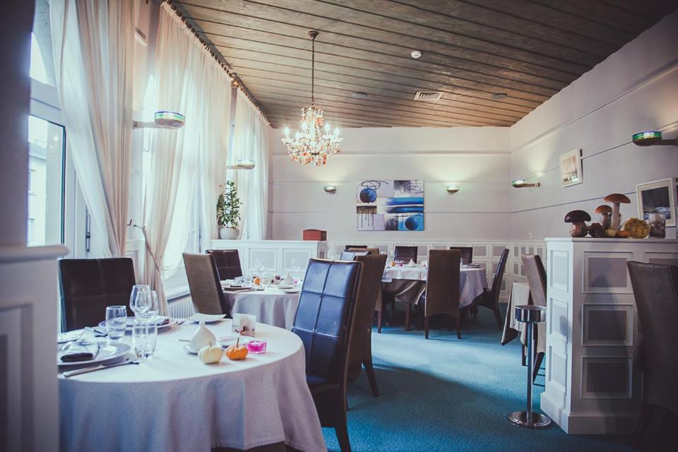 a dining room with tables and chairs and a chandelier at Hôtel Logis Le Bourbon in Yssingeaux