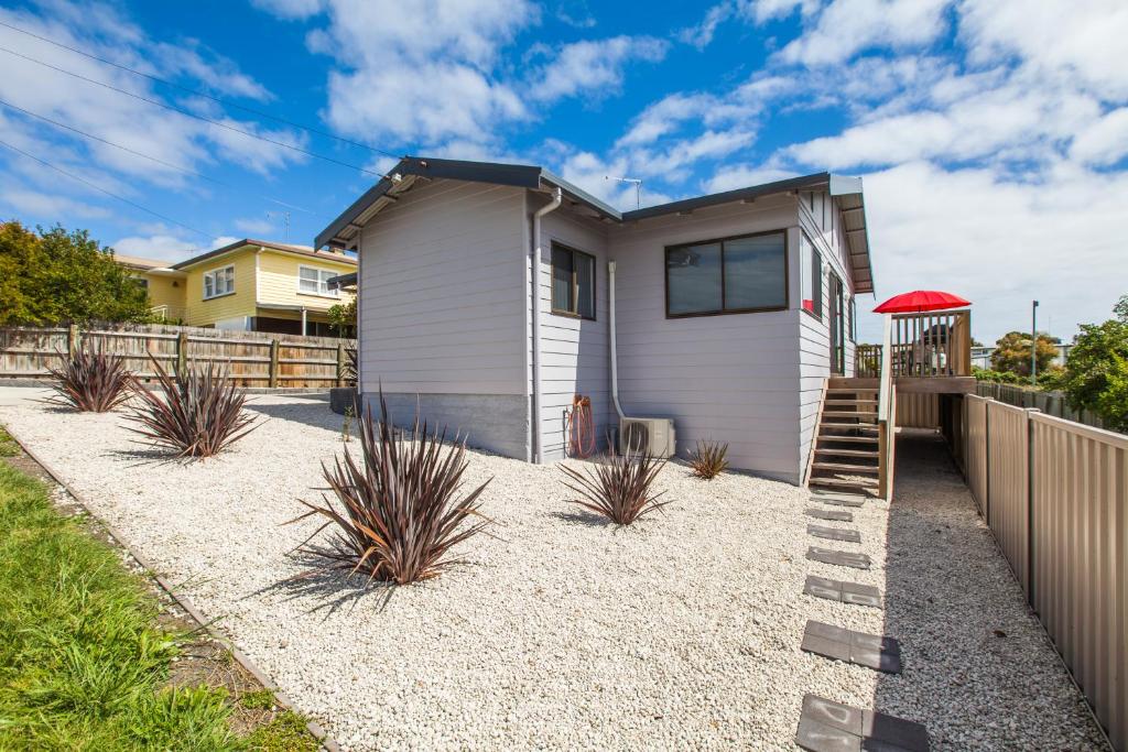 ein weißes Haus mit einer Treppe vor einem Zaun in der Unterkunft Bircoo Cottage Beach and Golf Getaway in Bridport