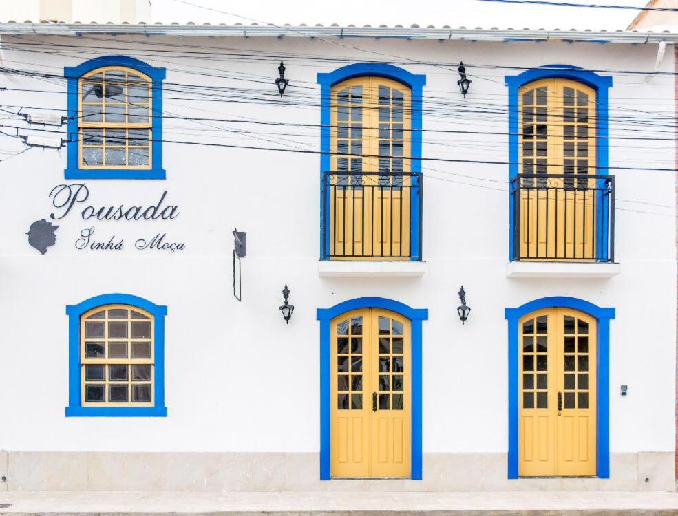 Pousada Sinhá Moça في ساو جواو ديل ري: مبنى أبيض بأبواب ونوافذ صفراء