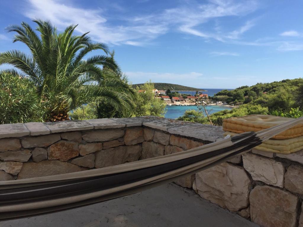 a stone retaining wall with a stone fence and palm trees at Bargujac Summer House in Vis
