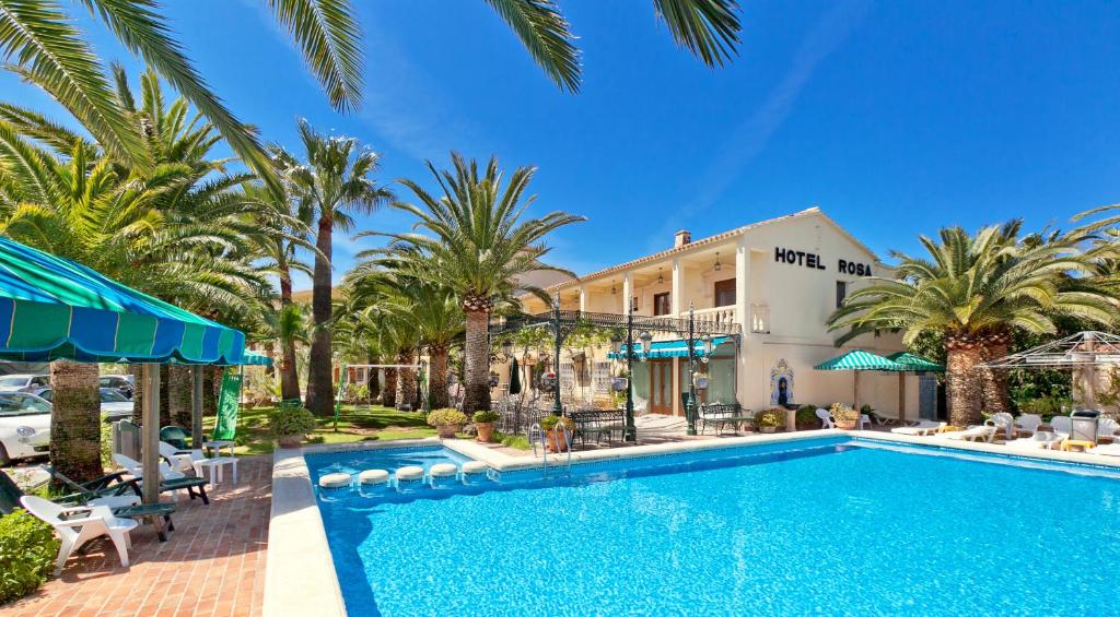 una piscina frente a un hotel con palmeras en Hotel Rosa en Dénia