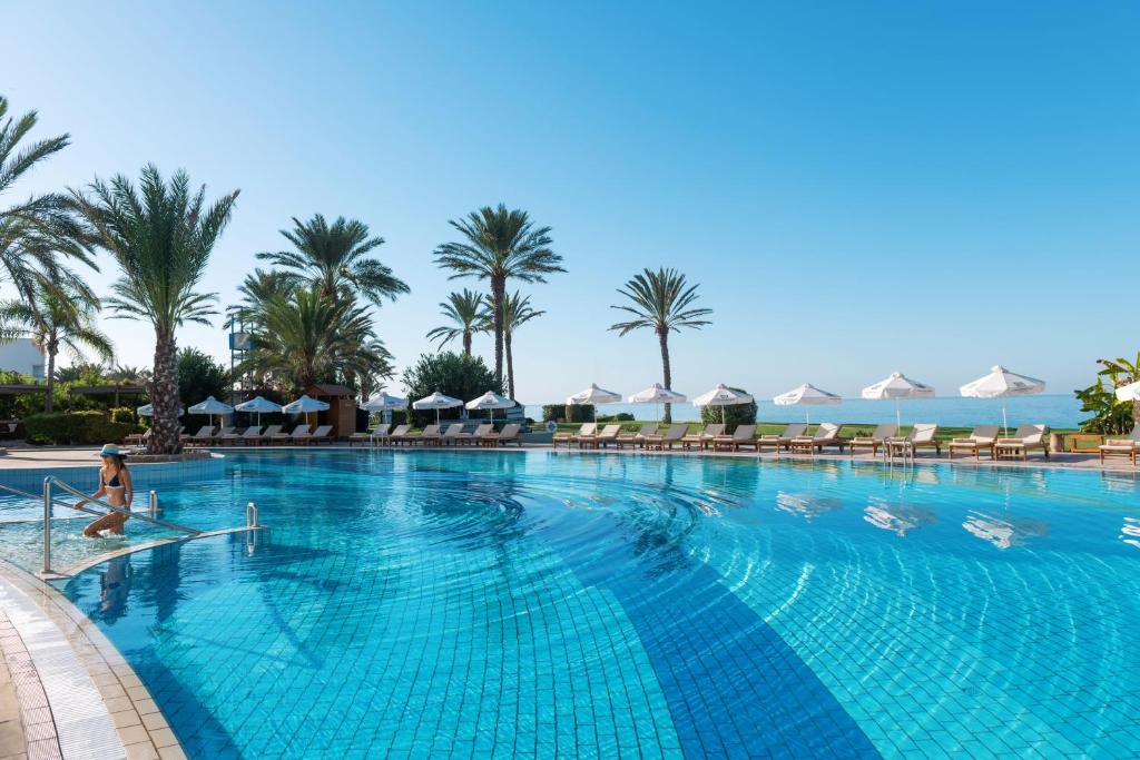 una mujer sentada en una piscina en un resort en Constantinou Bros Athena Beach Hotel, en Pafos