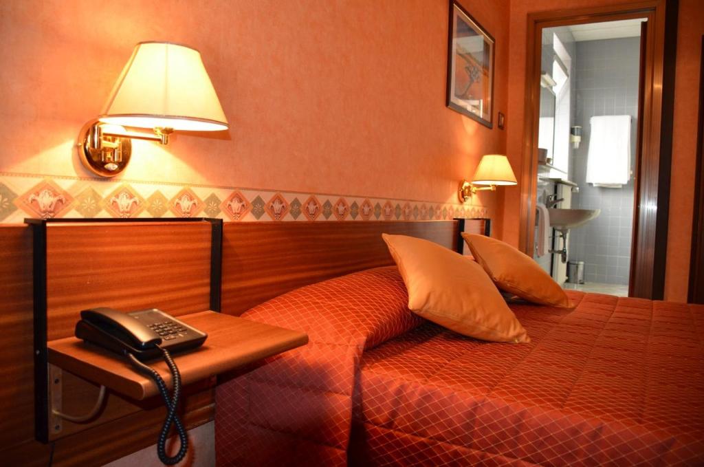 - une chambre avec un lit et un téléphone sur une table dans l'établissement Hotel Milano, à Trieste