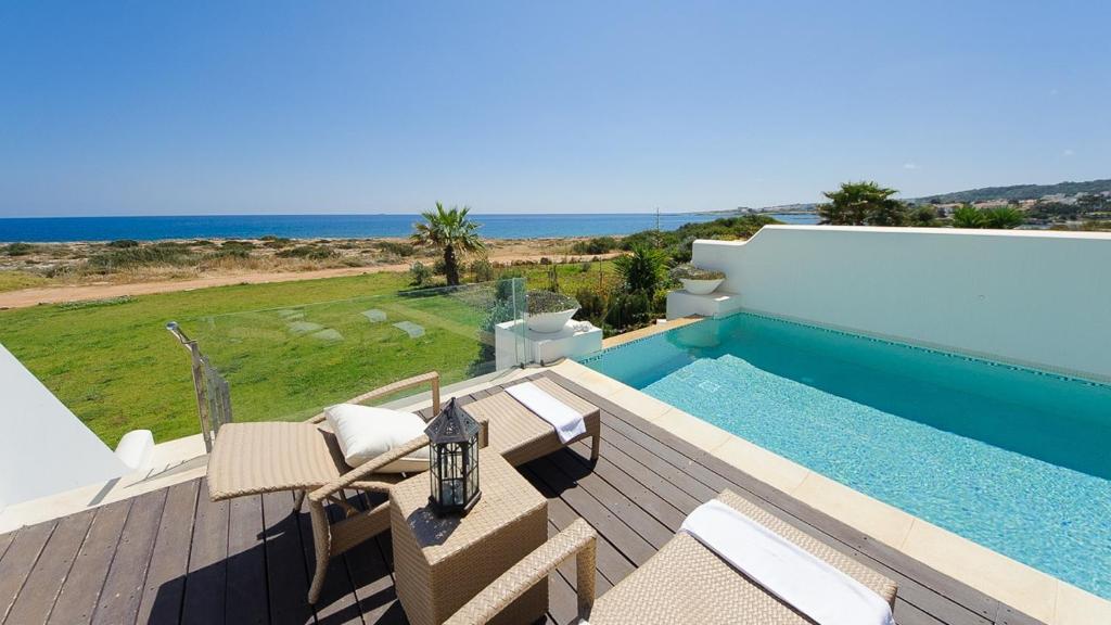 a swimming pool with chairs and a view of the ocean at Luxury Bay View Villa 28 Right On The Beach in Protaras