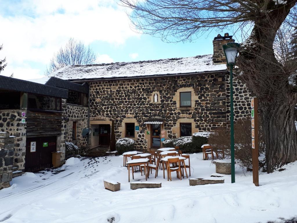 a stone building with tables and chairs in the snow at VVF Haute Loire Saint-Julien-Chapteuil in Saint-Julien-Chapteuil