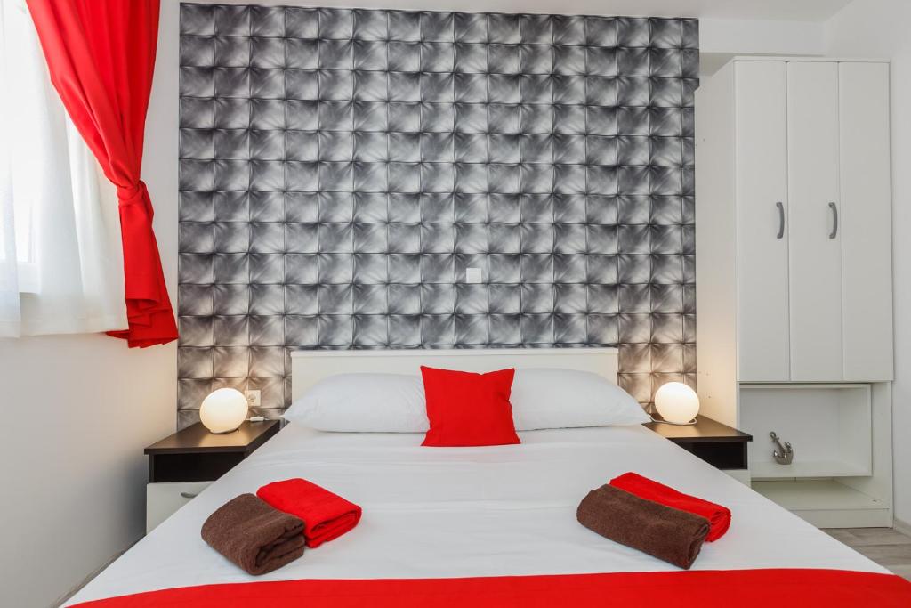 ein Schlafzimmer mit einem Bett mit zwei roten Kissen darauf in der Unterkunft Apartmani Nikola in Plano