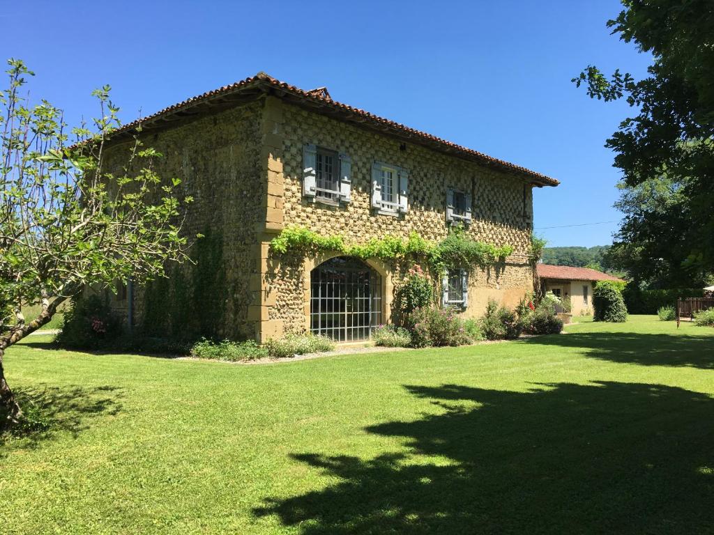 ein großes Steinhaus mit einem Rasenhof in der Unterkunft Les Tournesols in Sariac-Magnoac