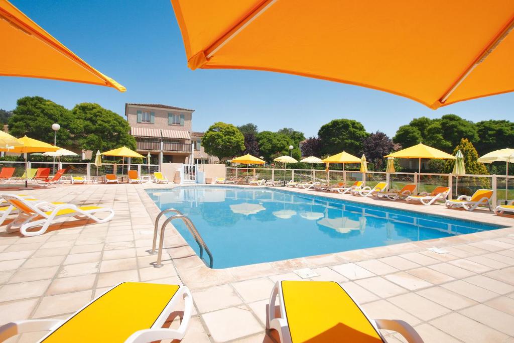 蒙托魯的住宿－Le Champ d'Eysson Aparthotel，一个带椅子和遮阳伞的游泳池