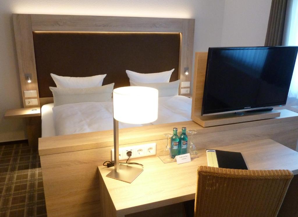 a hotel room with a bed and a desk with a television at Hotel-Restaurant Goldenstedt in Delmenhorst