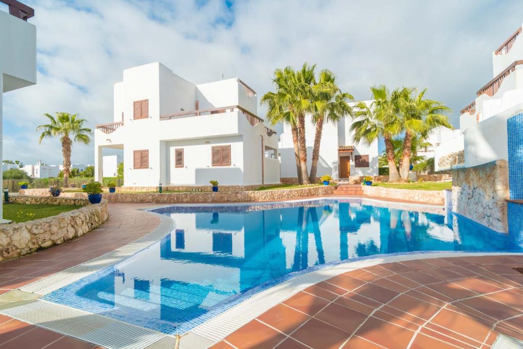 a villa with a swimming pool in front of a house at Marina D'Or IV Casa 5 in Cala d´Or