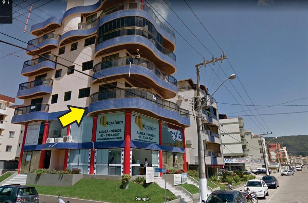 un edificio con una flecha amarilla en el costado en APTO 50M PRAIA NA AVENIDA - 6 PESSOAS, CHURRASQUEIRA, WIFI, SACADA, GARAGEM PARA VEICULOS PEQUENOS! - Residencial Roveda, en Bombinhas