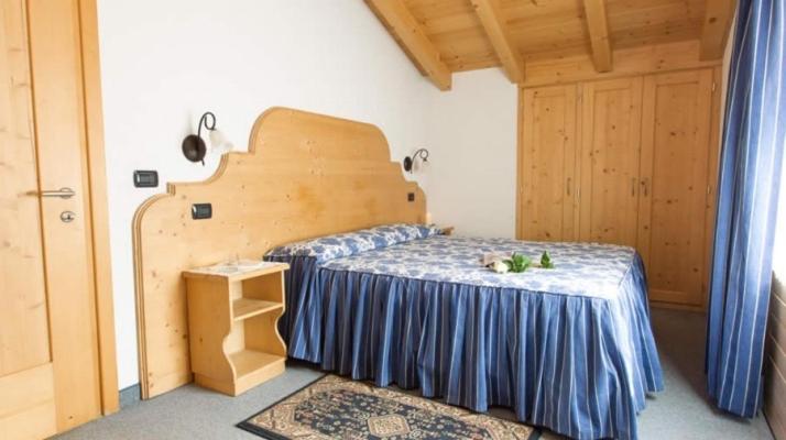 sypialnia z łóżkiem z niebieską narzutą w obiekcie Tea Bastian w Livigno