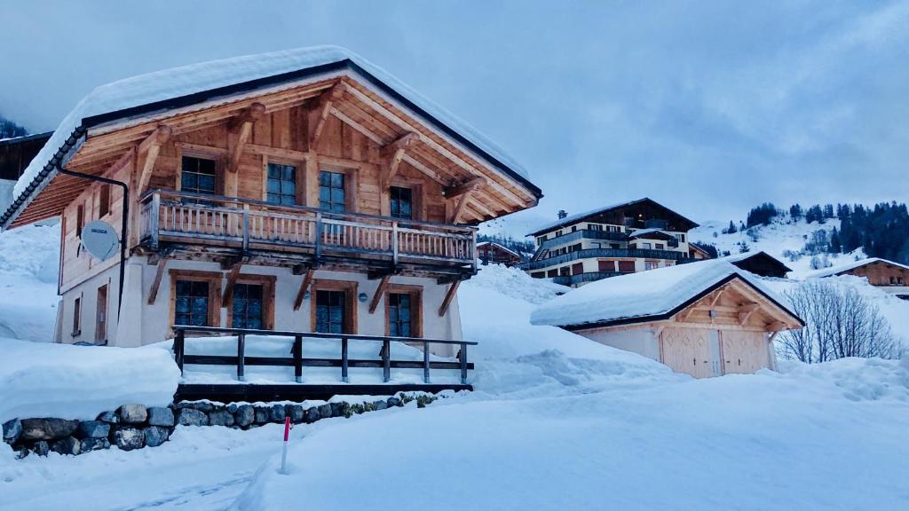 duży drewniany budynek z balkonem w śniegu w obiekcie Chalet Ange w mieście La Giettaz