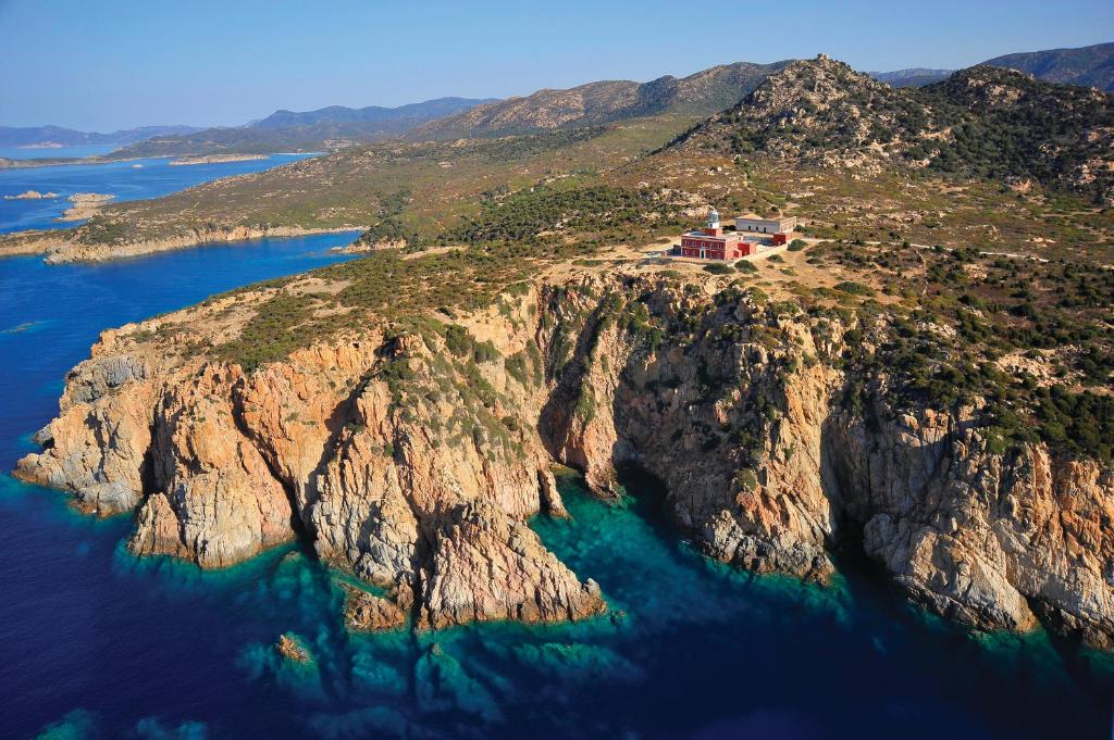 an island in the ocean with a house on it at Faro Capo Spartivento in Chia