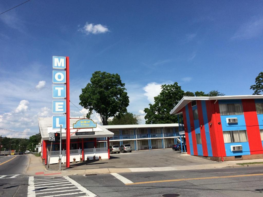 un edificio con un cartel de motel al lado de un estacionamiento en Village Motel, en Ellenville