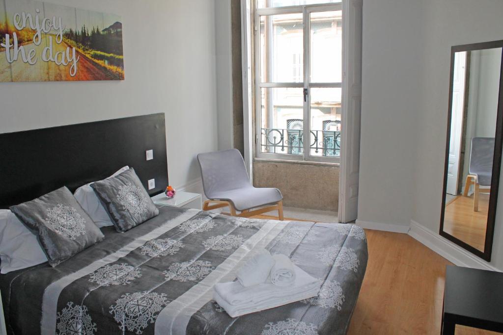 a bedroom with a bed and a chair and a window at Lunar Guest House in Porto