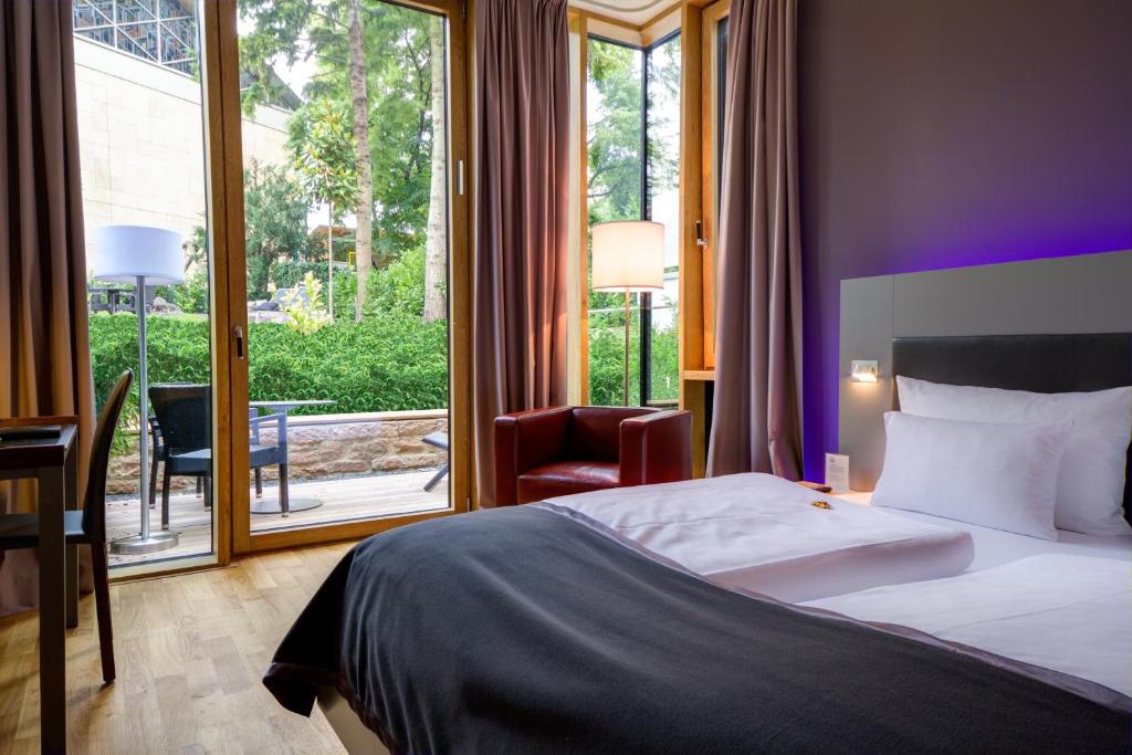 ハイデルベルクにあるQube Hotel Bergheimのベッドと大きな窓が備わるホテルルームです。
