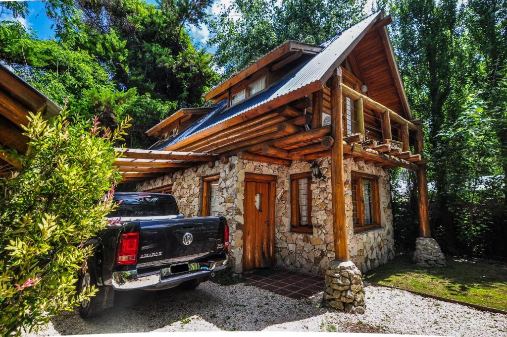 a truck parked in front of a log cabin at Cabañas Cumelen in Villa Gesell