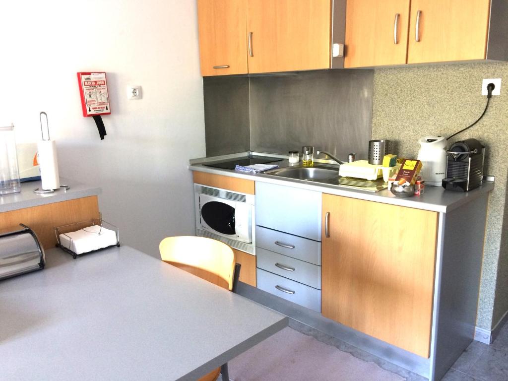 a small kitchen with a sink and a microwave at Ericeira Surf and Sun in Ericeira