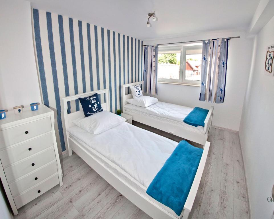 um pequeno quarto com 2 camas e uma cómoda em Apartamenty Baltico Ustka em Ustka