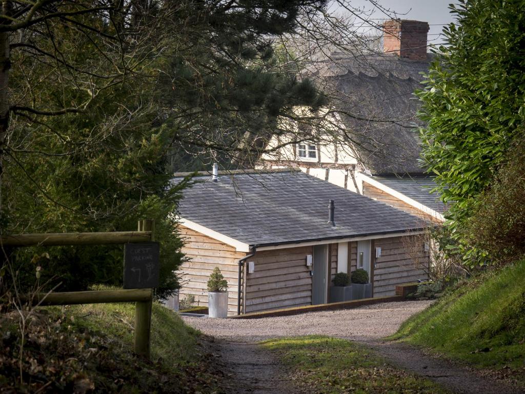 una cabaña de madera con un cartel delante en The Steppes Holiday Cottages en Hereford
