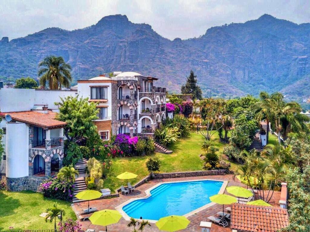 a mansion with a swimming pool and mountains in the background at Posada del Tepozteco - Hotel & Gallery in Tepoztlán