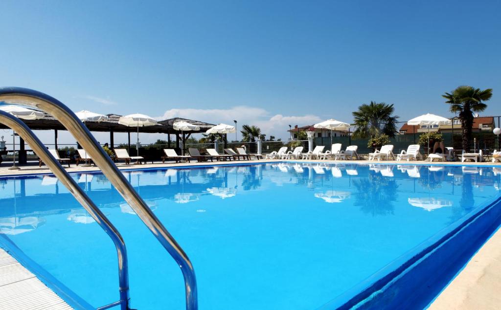 une grande piscine bleue avec des chaises et des parasols dans l'établissement Villa Gloria, à Poreč