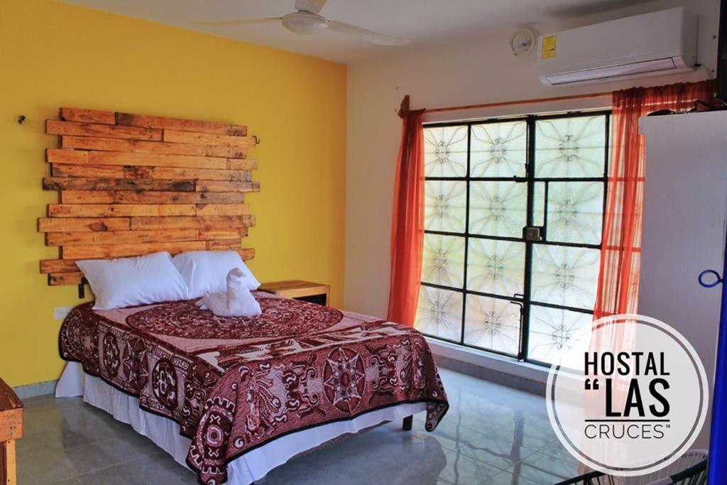 a bedroom with a bed with a wooden headboard and a window at Hostal Las Cruces in Valladolid