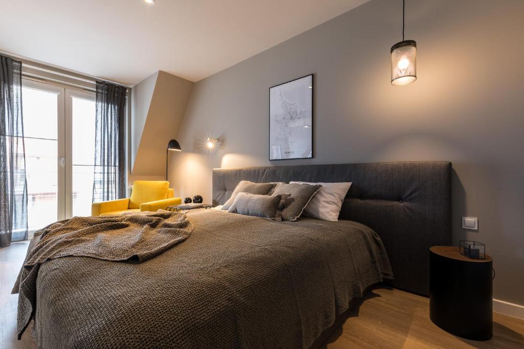 a bedroom with a large bed and a yellow chair at Tartaczna Street Apartment in Gdańsk