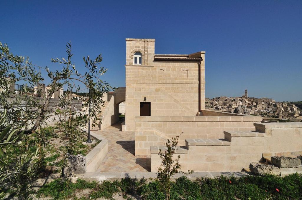 ein kleines Backsteingebäude mit einem Turm auf einem Hügel in der Unterkunft Torretta ai Sassi in Matera