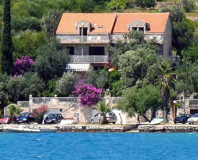 a large house with cars parked in front of the water at Vila Luka in Slano