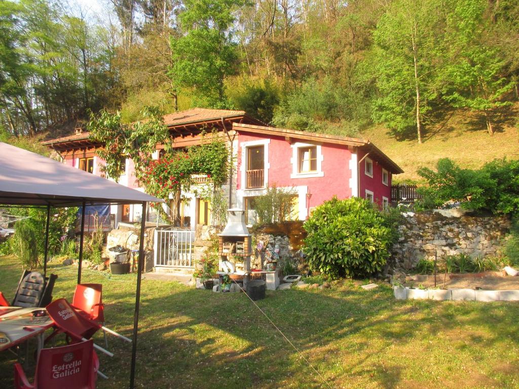 una pequeña casa roja en un patio con una tienda de campaña en La Muria Apartment, en Cangas de Onís