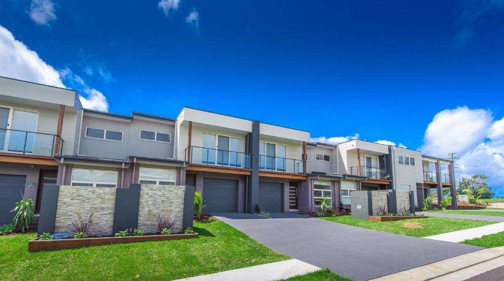 a row of apartment buildings on a sunny day at Escape At Nobbys Executive Townhouse 1 74 Pacific Drive in Port Macquarie