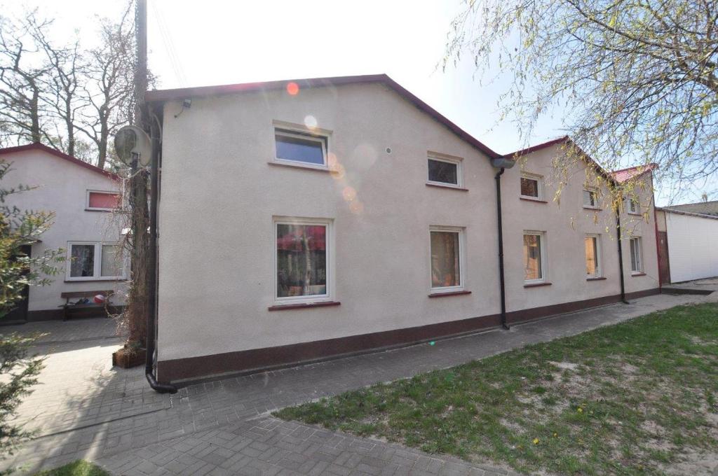 a large white house with windows on a street at Gościniec rybacki in Dąbki