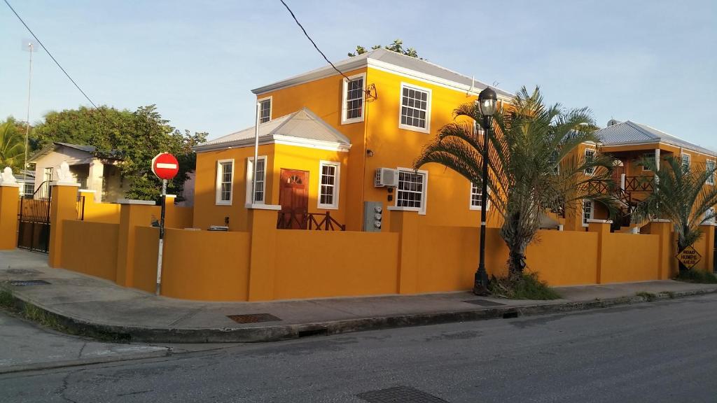 a yellow house with an orange fence on a street at Frontline Apartments in Christ Church