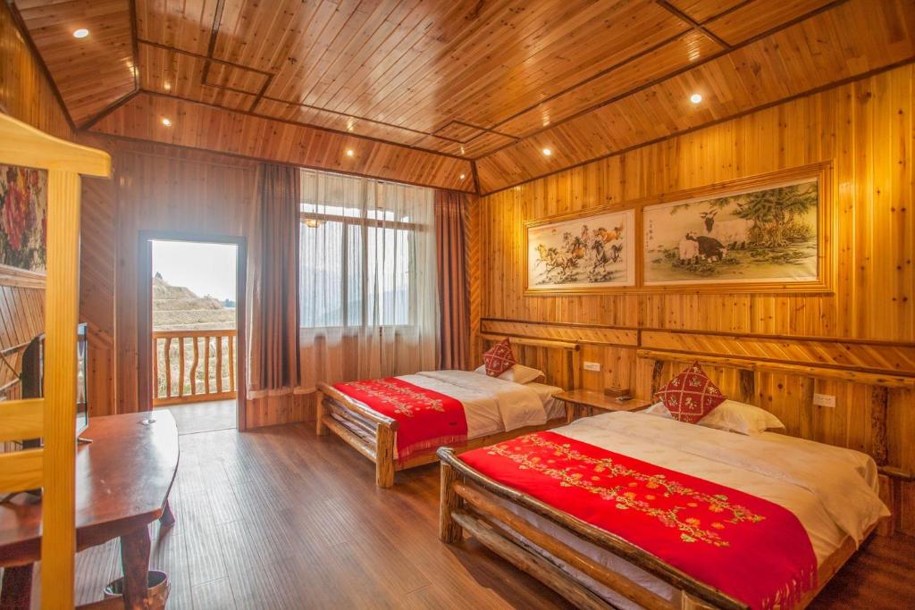 two beds in a room with wooden walls and wooden floors at Long An Hotel in Longsheng