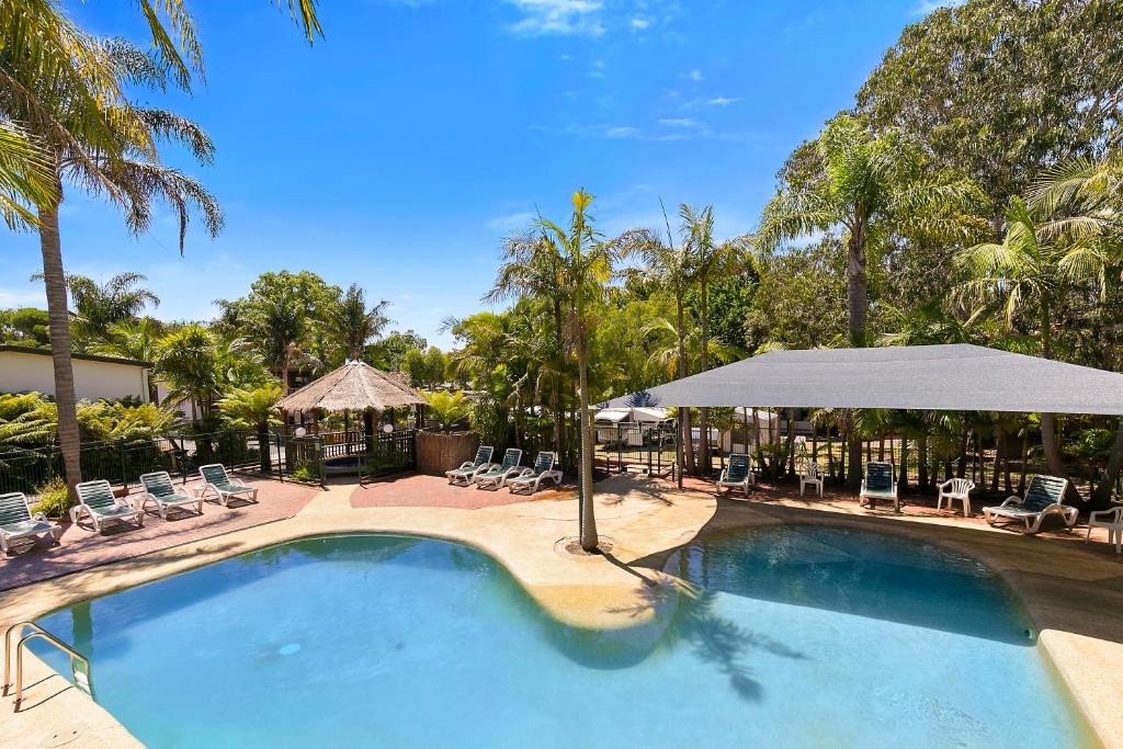 una grande piscina con sedie e ombrelloni di Kaloha Holiday Resort Phillip Island a Cowes