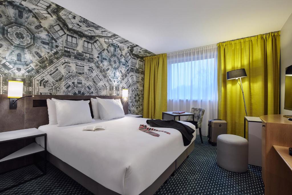 ロワシー・アン・フランスにあるメルキュール パリ ロワシー CDGの大きなベッドとデスクが備わるホテルルームです。