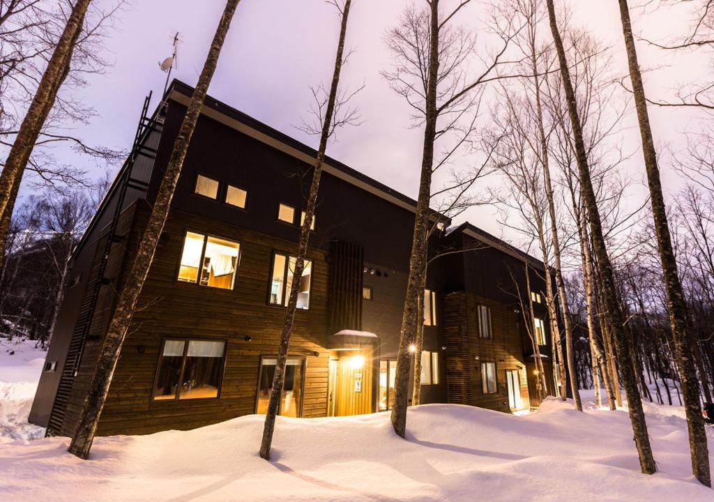 a wooden house in the snow in the woods at SnowDog Village in Niseko