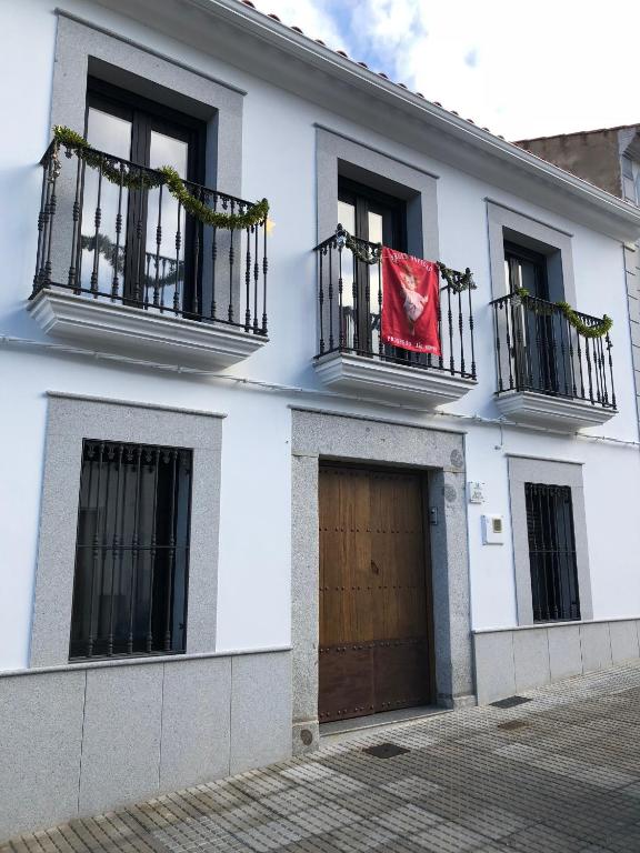 a white building with a red flag on a balcony at La Casa de las Tias in Villanueva de Córdoba