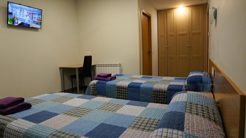 a hotel room with two beds and a tv at Pensión Calfred II in Logroño