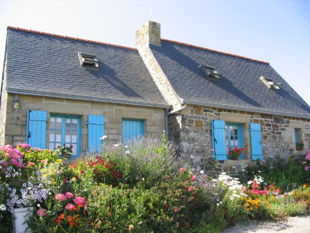 una casa de piedra con puertas azules y flores en lemoign-locations, en Crozon