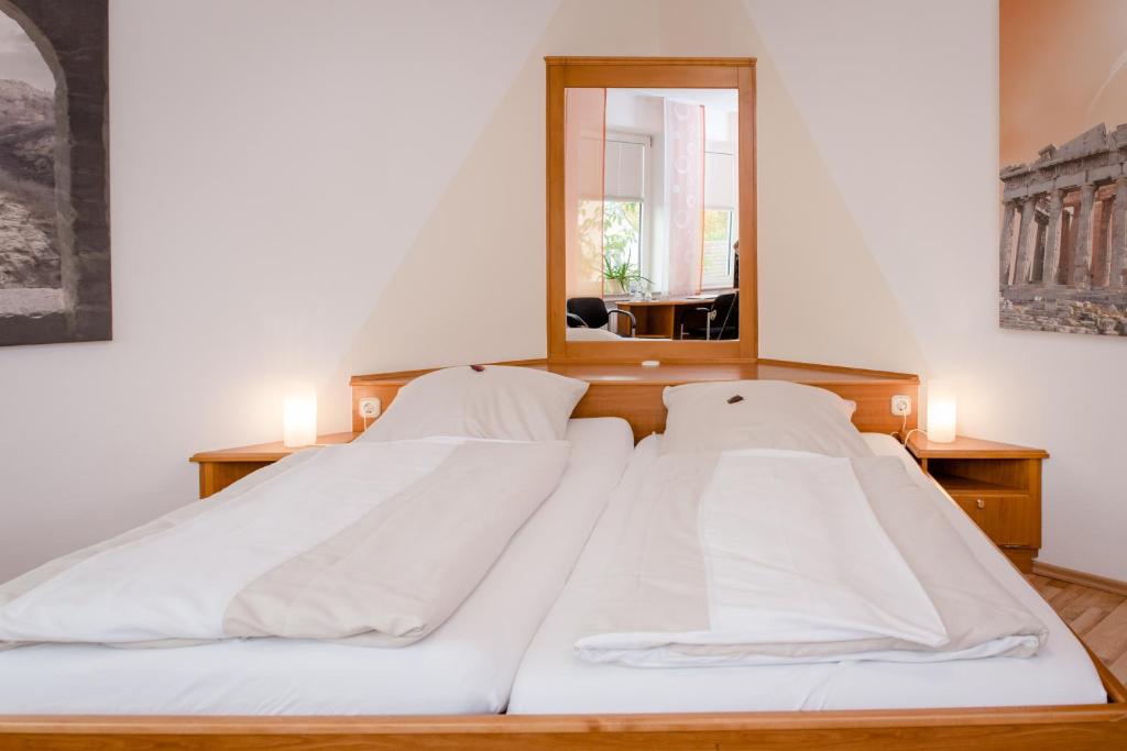two white beds in a room with a mirror at Hotel Handelshof in Bünde