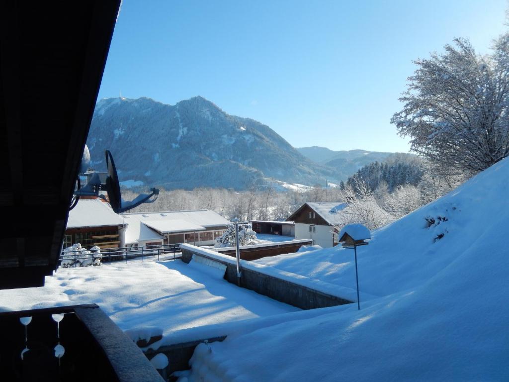 um quintal coberto de neve com casas e montanhas ao fundo em Ferienwohnung Lehmann em Blaichach