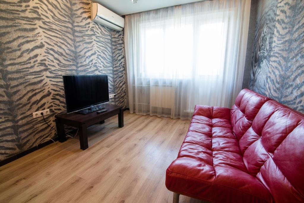 a living room with a red couch and a television at Apartments on Kirova 76 in Novokuznetsk